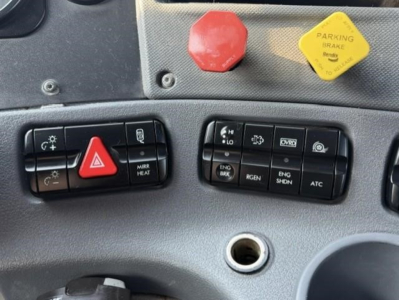 Dashboard control panel of a 2019 Freightliner Cascadia 126 with red emergency switch, yellow parking brake cap, and various switches labeled hazard, mirror heat, ENG BRK, etc.