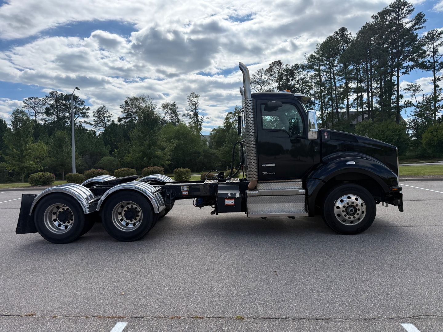 Kenworth T880 conventional daycab truck side view showing cab, fuel tanks, exhaust stack, dual rear axles, and chrome wheels.