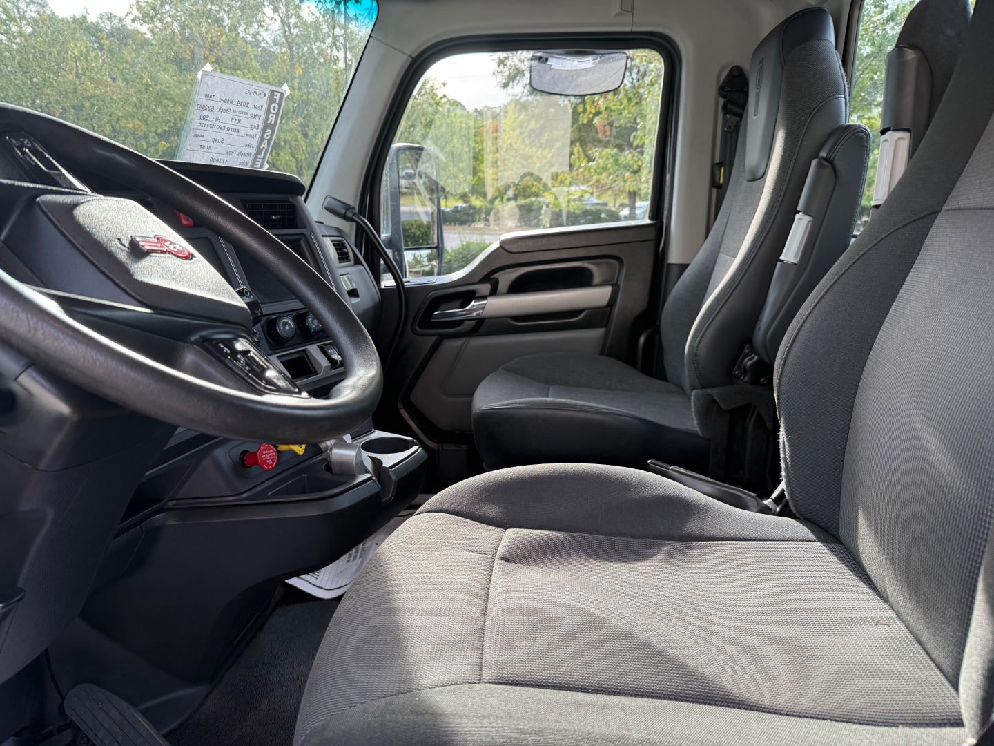 Kenworth T880 truck interior front cockpit and passenger seat view, steering wheel, dashboard, and driver and passenger seats visible.