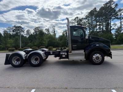Kenworth T880 conventional daycab truck side view showing cab, fuel tanks, exhaust stack, dual rear axles, and chrome wheels.