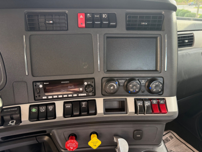 Dashboard of a Kenworth T880 cab showing switches, climate controls, infotainment, and warning buttons; visible text includes hazard button, HVAC dials, Kenworth radio, and various control labels.