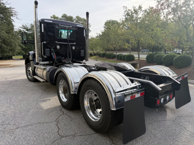 Kenworth T880 cab with dual rear axles showing chrome fuel tanks, mud flaps, and rear hitch area; side and back view of tractor chassis.