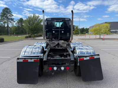 Kenworth T880 tractor rear view showing chrome fenders, dual exhaust stacks, rear lights, and mud flaps; metal chassis and coupler visible.