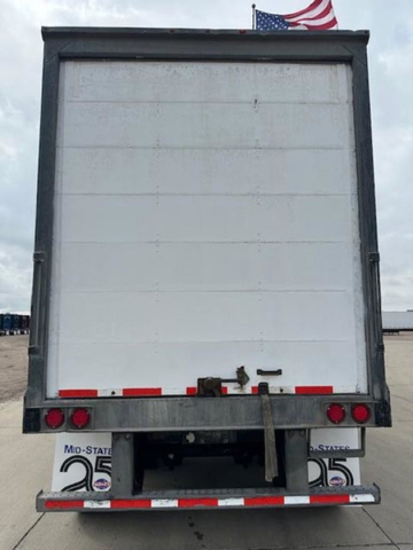 Rear view of a 2014 Wabash van trailer showing blank white back door, small taillights, and bumper with reflective tape.