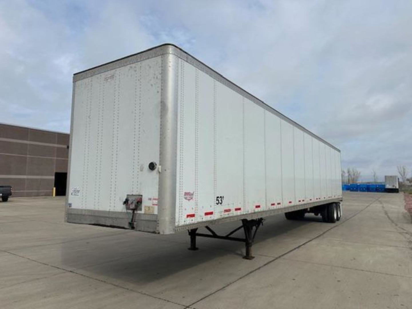 Trailer body showing a 53' dry van with wheels underneath and landing gear in a parking lot.