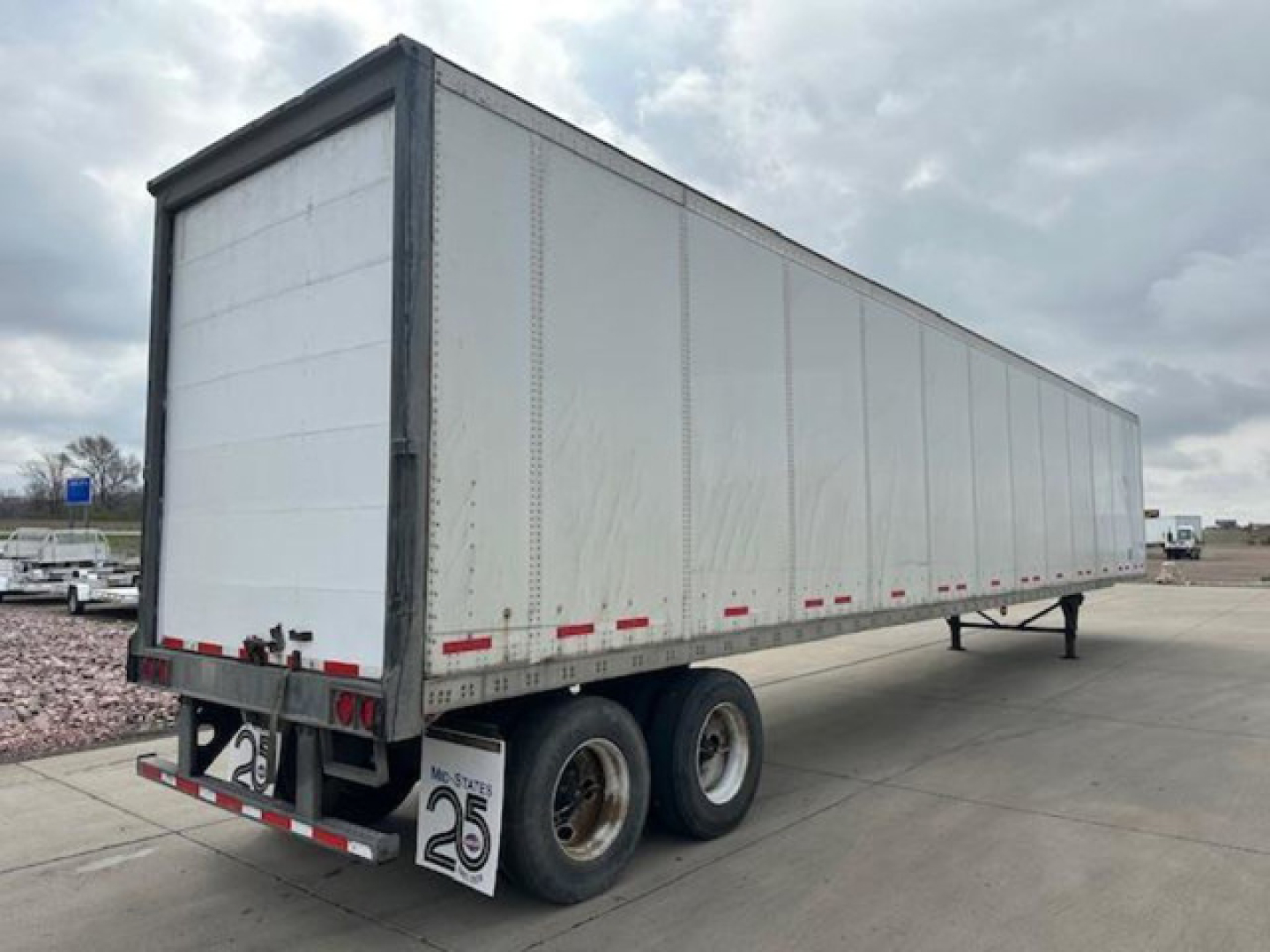 Trailer side view: 2014 Wabash van dry trailer with white aluminum panels, dual rear axles, and landing gear visible.