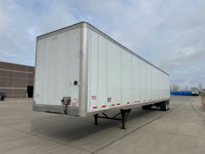 Trailer body showing a 53' dry van with wheels underneath and landing gear in a parking lot.