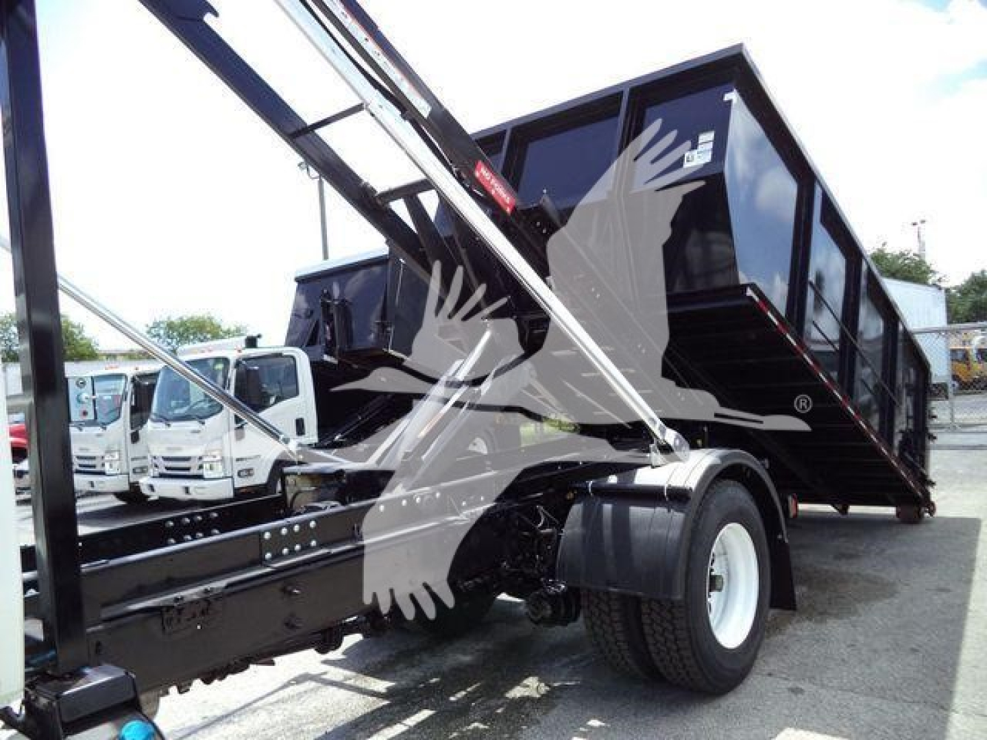 Truck side view showing a 2019 International 4300 roll-off with a raised bed and hydraulic crane components.