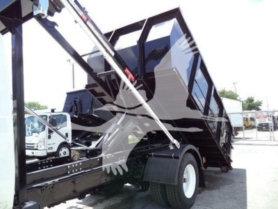Truck bed area of a 2019 International 4300 rollover dump with hydraulic arms and cargo container visible.