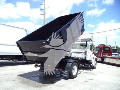 Truck appears with a raised dump bed on a white cab, International 4300, in a lot.