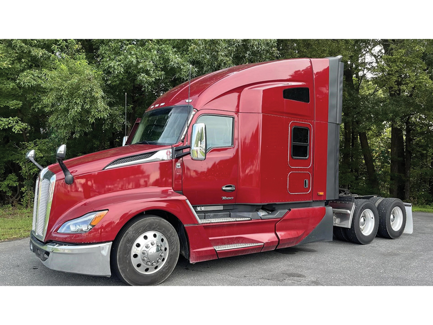 Kenworth T-680 Next Gen sleeper tractor in red, side view showing cab with aerodynamic panels and chrome mirrors.