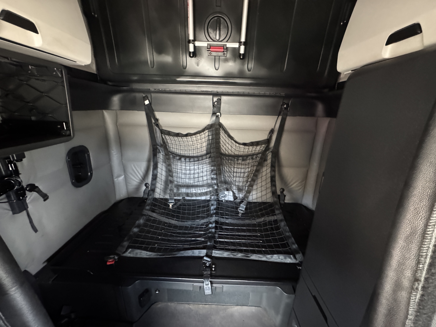 Freightliner Cascadia cab interior showing sleeper berth with cargo net and storage compartments.