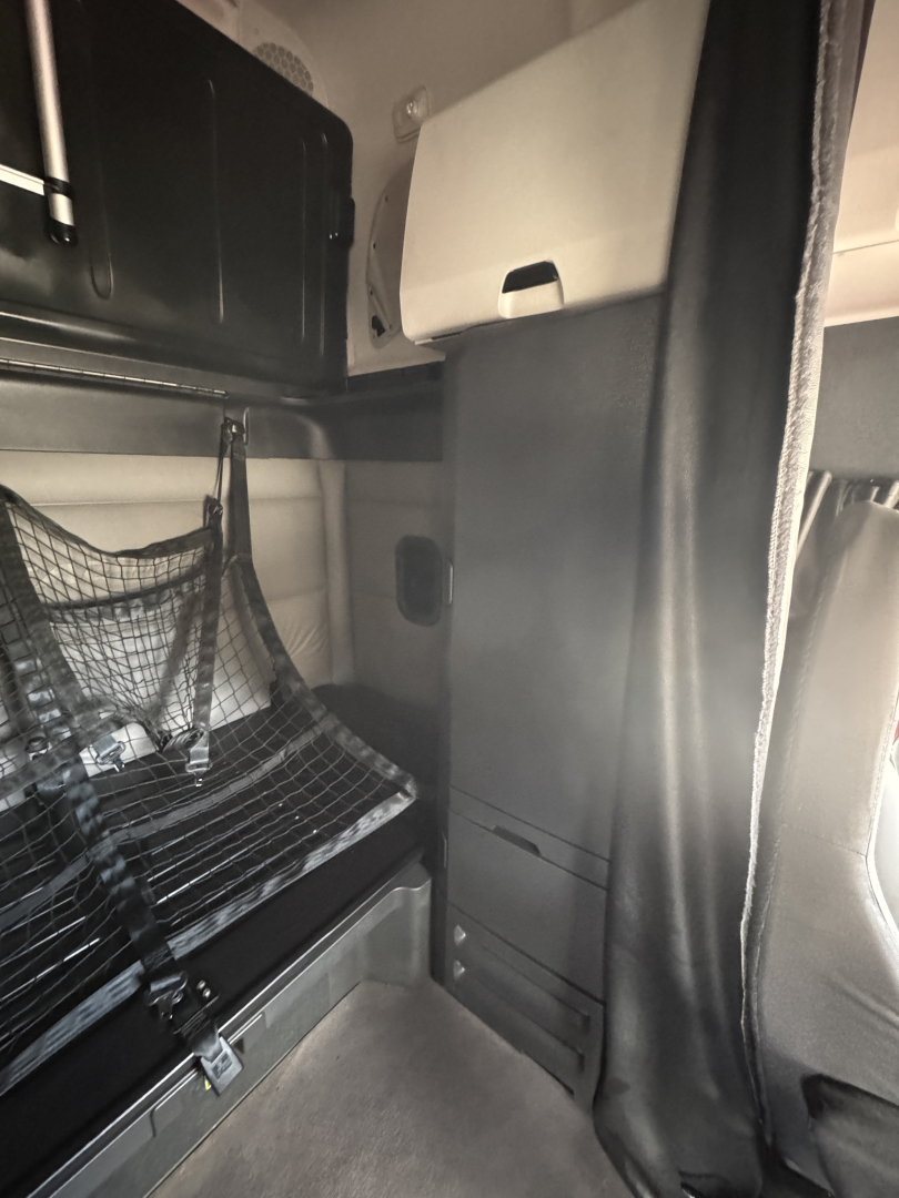 Cab interior of a Freightliner Cascadia 126 sleeper showing storage cabinets and driver area