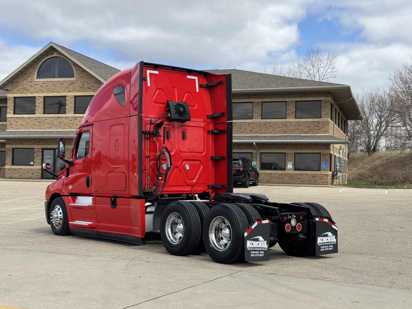 Freightliner Cascadia 126 tractor rear/side view showing chassis and fifth wheel area, red paint, dual rear axles, chrome wheels, mud flaps, and cab detailing.