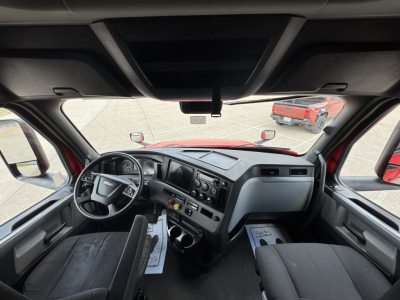 Interior driver area of a Freightliner Cascadia 126, view from the cab with steering wheel, dashboard, and seats visible.