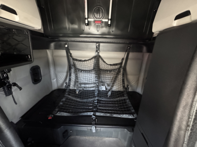 Freightliner Cascadia cab interior showing sleeper berth with cargo net and storage compartments.