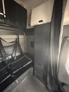 Cab interior of a Freightliner Cascadia 126 sleeper showing storage cabinets and driver area