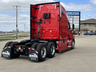 Truck rear-right view of a red Freightliner Cascadia 126 sleeper cab tractor with dual rear axles and mud flaps.