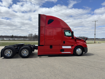 Freightliner Cascadia 126 sleeper cab tractor side view with red paint and chrome wheels.