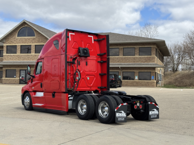 Freightliner Cascadia 126 tractor rear/side view showing chassis and fifth wheel area, red paint, dual rear axles, chrome wheels, mud flaps, and cab detailing.