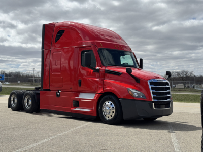 Freightliner Cascadia 126 red semi-truck in a parking lot, side view showing sleeper cab, chrome front grille, black bumper, dual rear axles.