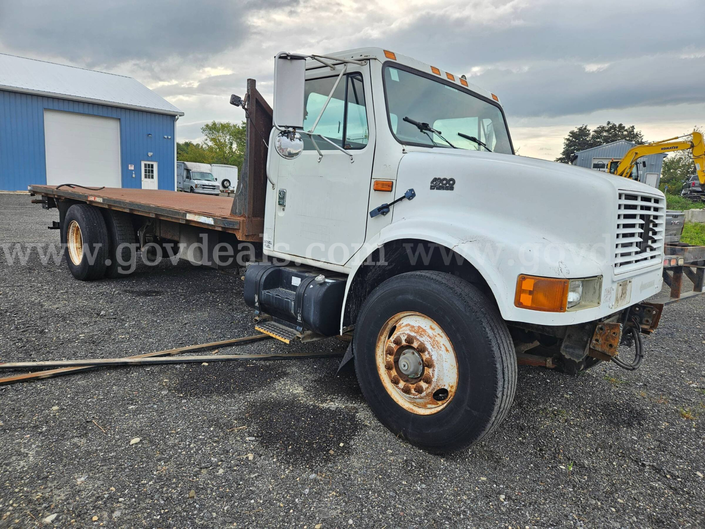 International 4900 flatbed dump truck in-service showing front grille, cab, and long flatbed with wheel wells and rust on rims.