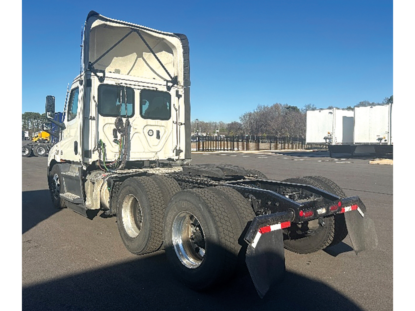 Truck chassis with rear dual axles and raised cab of a 2022 Freightliner Cascadia116 showing the flatbed fifth wheel area.