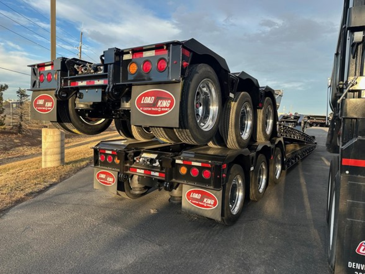 Trailer stack: Load King Ss lowboy trailer with triple-axle configurations and Load King logo mudflaps.