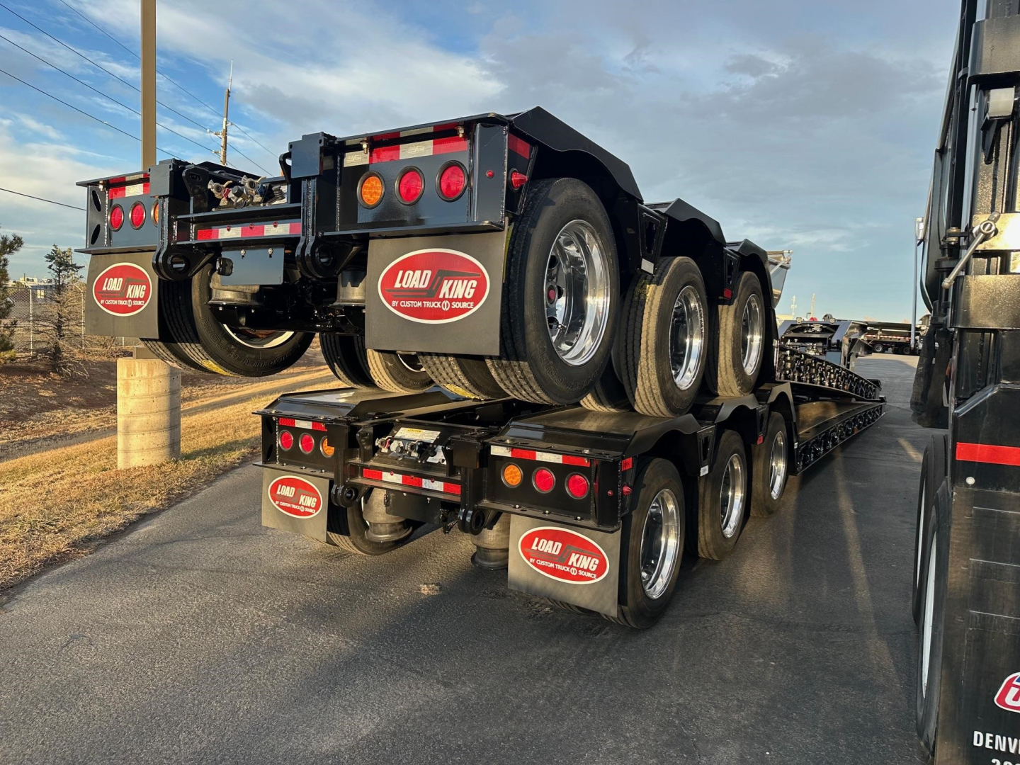 Load King trailer stack showing multiple axles, with red and white Load King logos on mudflaps and rear bumper.