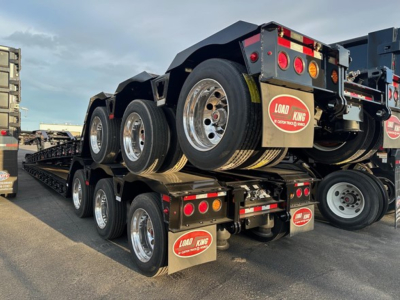 Trailer axles and load king lowboy trailer with dual rear tandems and Load King branding on mudflaps.