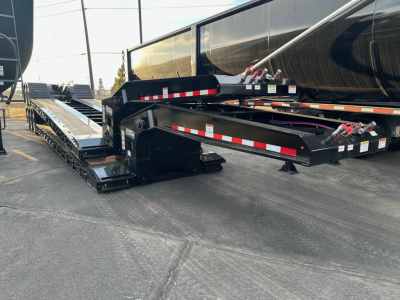 Load King trailer lowboy deck showing black structural frame with red-and-white reflective striping and a hydraulic gooseneck area.