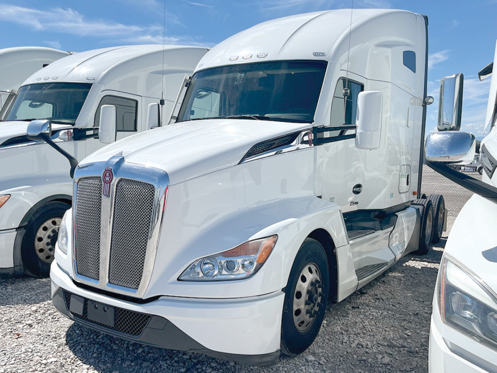 Truck image: white 2023 Kenworth T680 Next Gen tractor cab, front view showing grille, headlights, and side mirrors.
