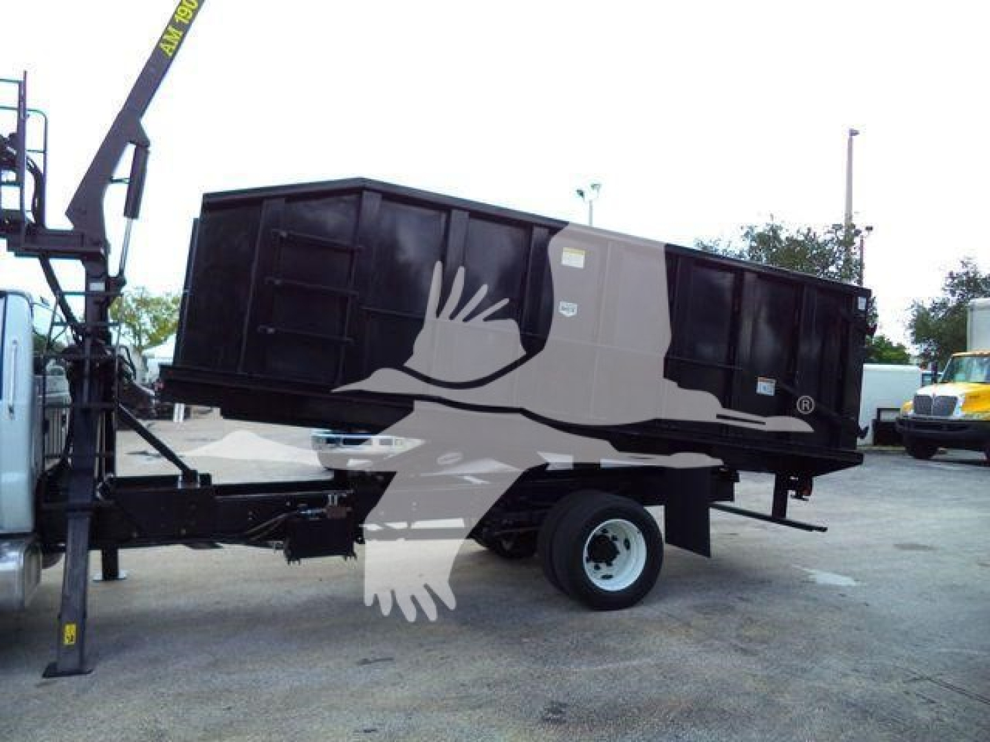 Grapple truck bed on a Ford F650 chassis in a dealership lot, flatbed/dump style with a crane arm nearby.