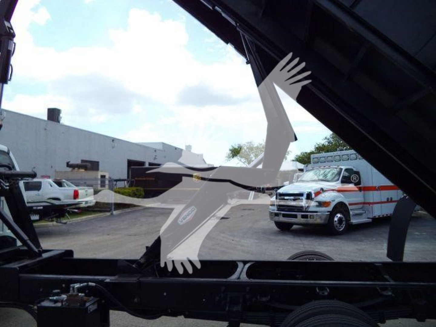 2023 Ford F650 Sd truck in stock lot with grapple equipment visible and service vehicles in background.