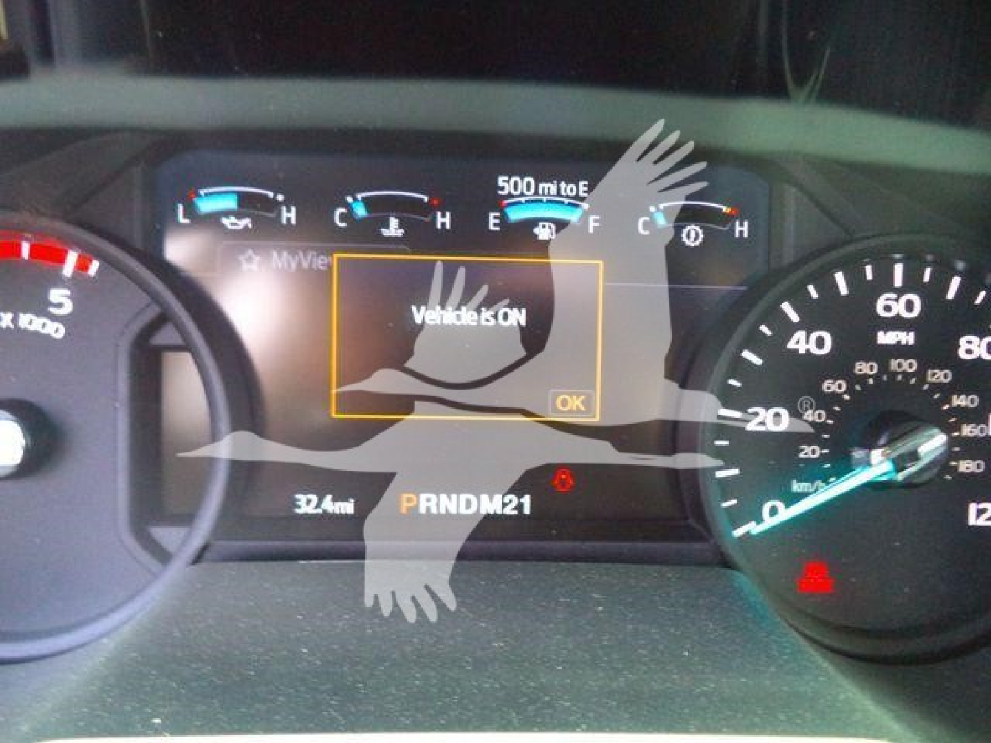 Truck dashboard showing center LCD with 'Vehicle is ON' warning, gear indicator PRNDM21, odometer 32.4mi, speedometer on right, fuel gauge on top center.