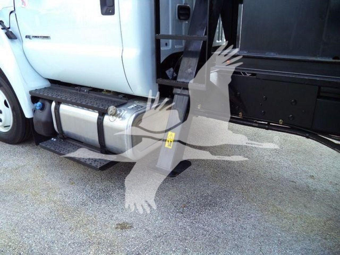 Truck side view showing step bar, fuel tank, and grapple attachment on 2023 Ford F650 with white cab and black equipment area.