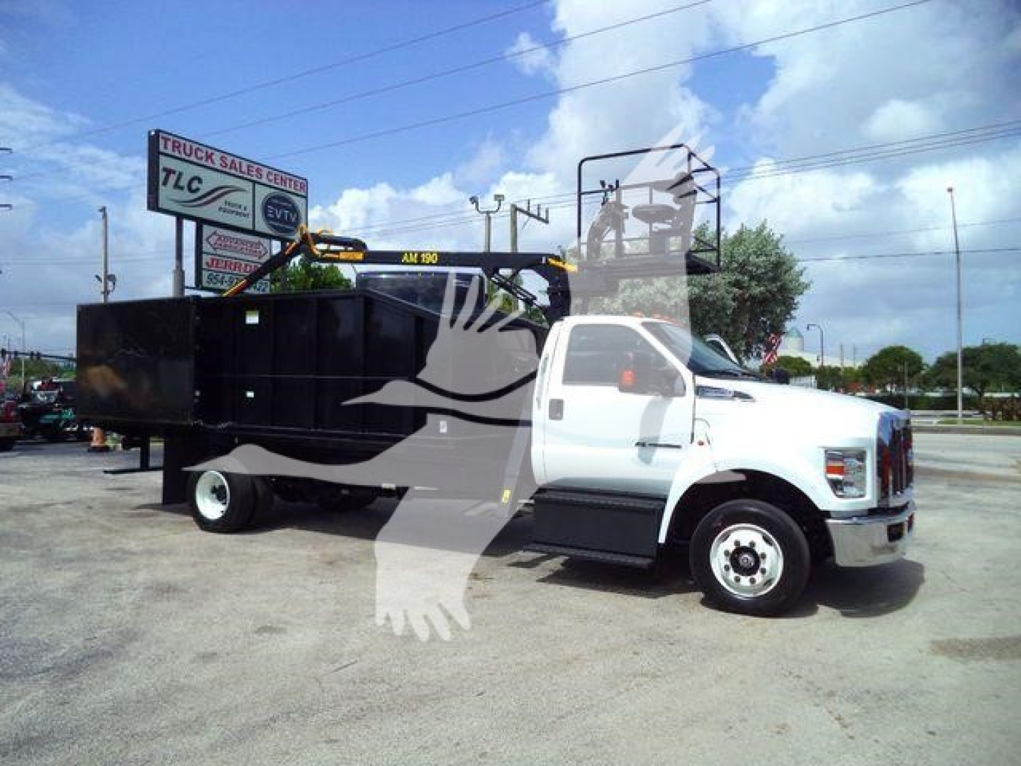 Ford truck with a grapple attachment in a truck lot, white cab, black grapple bed, crane and lifting arm visible