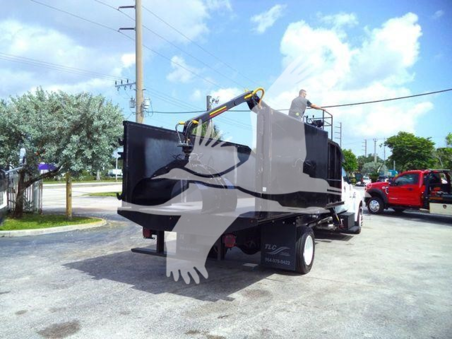 Ford F650 grapple truck with hydraulic arm, side view showing dumping bed and grapple gear, white and black color scheme.