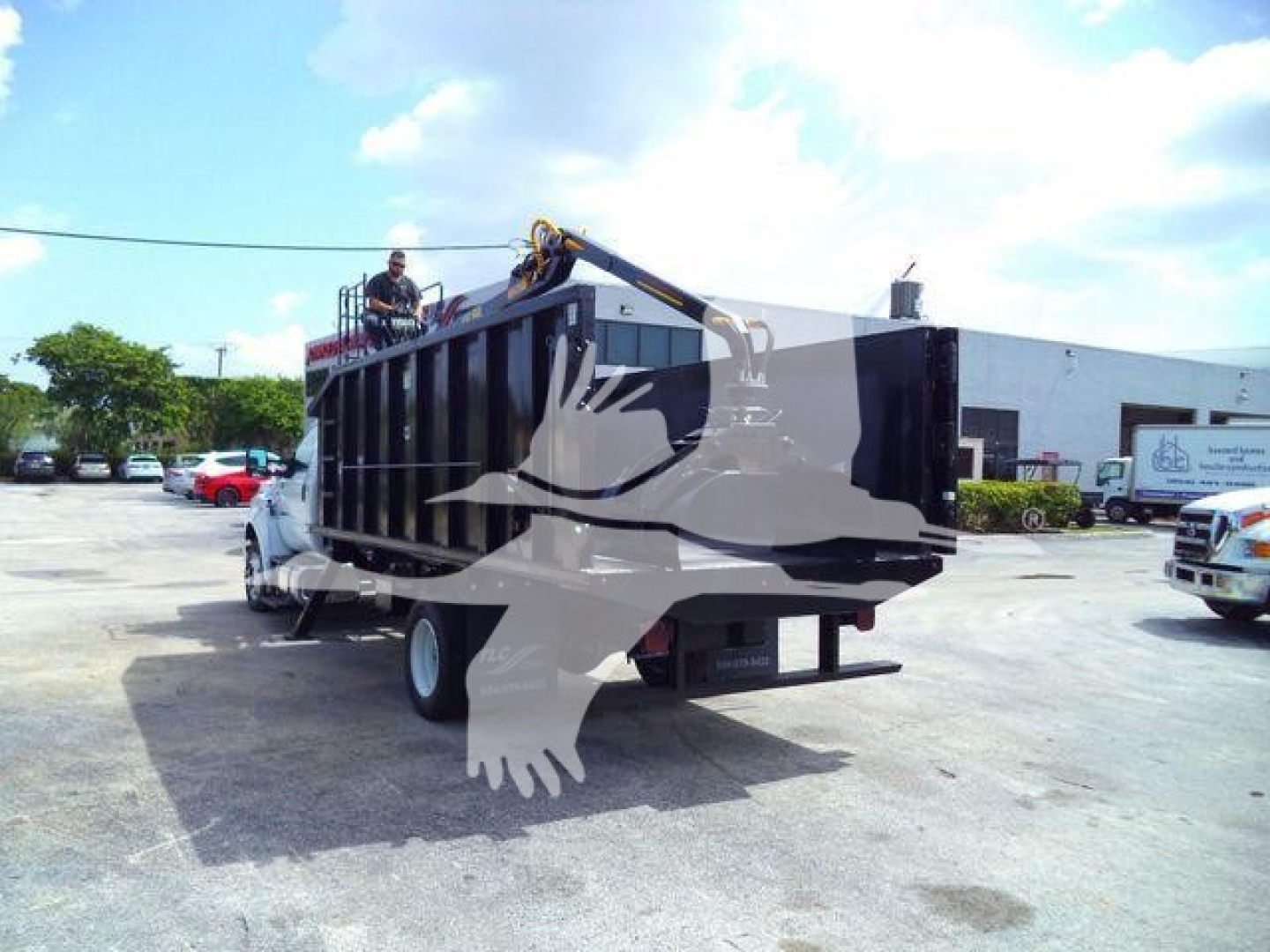 Ford F650 dump truck with grapple in rear, back view showing hydraulic grapple arm and truck bed; no visible text legible.