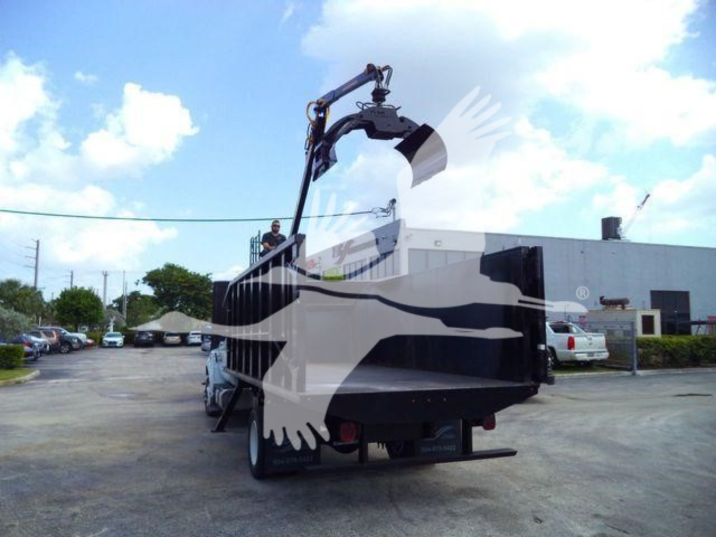 Ford F-650 grapple truck showing hydraulic grapple arm and rear hitch in a dealership lot.