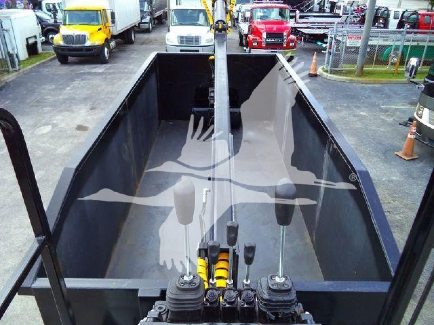 Open bed of a 2023 Ford F650 grapple truck showing control levers and hydraulic cylinders inside the bed with surrounding rails