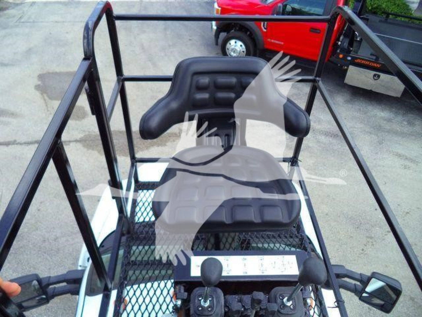 Ford F650 grapple truck cockpit with elevated seat and protective cage, visible levers and control panels.