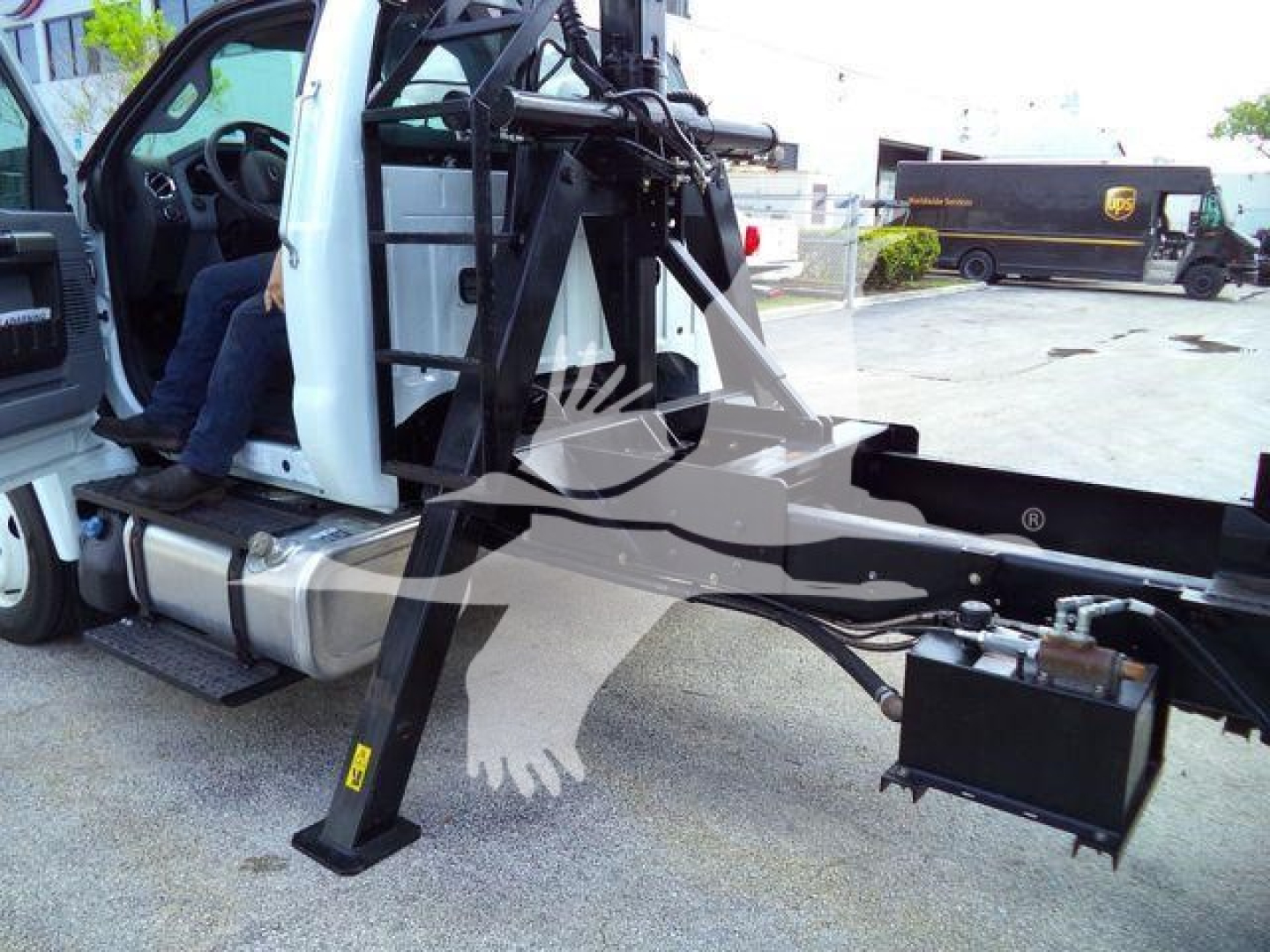 Ford F650 truck cab with grapple arm and hydraulic lines visible, side view showing operator seat, steps, and chassis components.