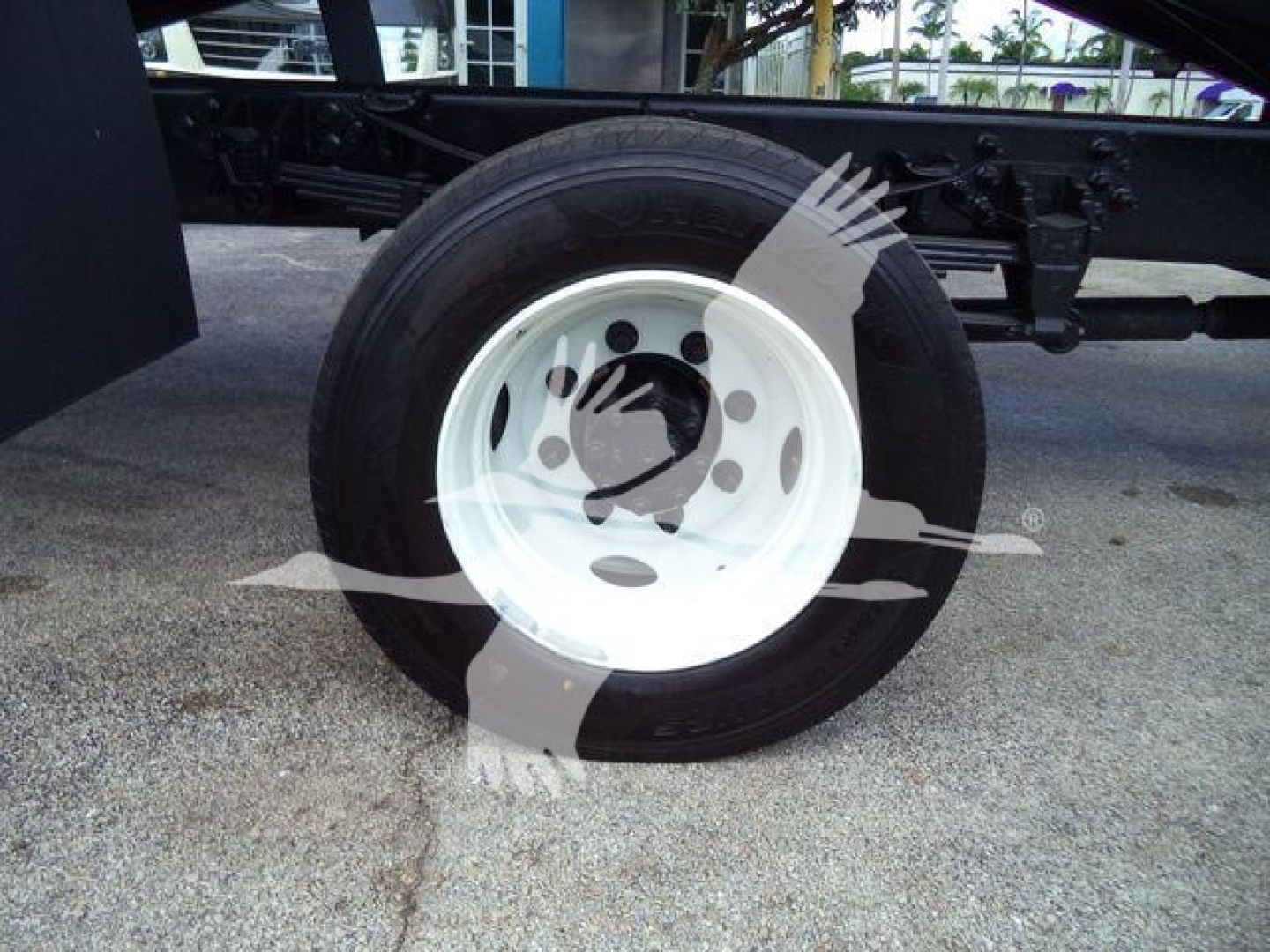 Truck wheel with white rim and black tire; part of a chassis frame visible in background.