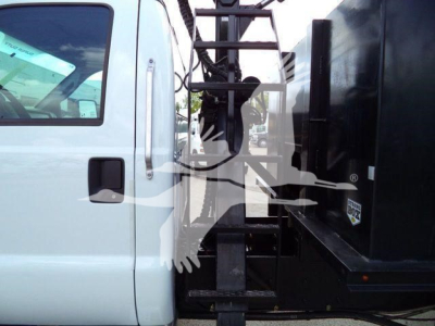 Ford F650 grapple truck cab with hydraulic grapple equipment visible beside the cab in a white/black color scheme.