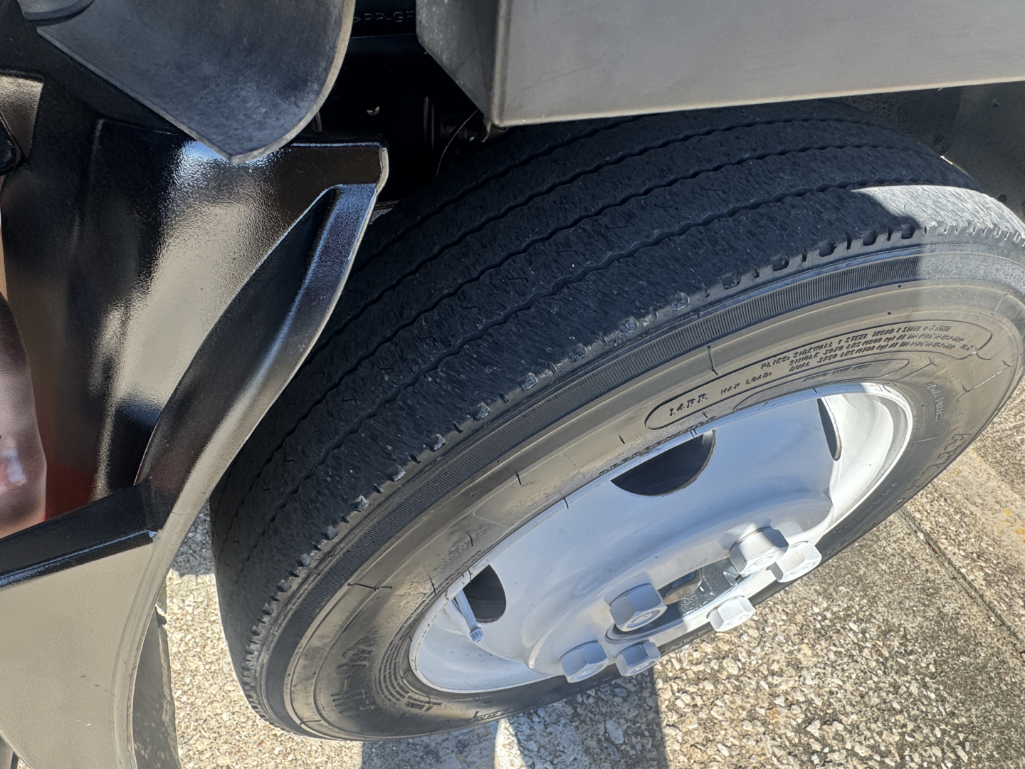Isuzu NPR-HD truck wheel and fender close-up showing tire and wheel hub with lug nuts.