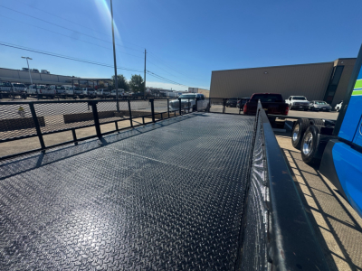 Isuzu NPR-HD flatbed truck bed with diamond plate steel surface and side rails visible in a dealership lot.