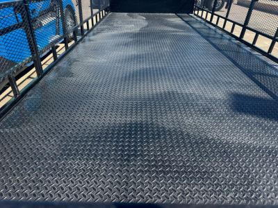 Isuzu NPR-HD flatbed truck bed showing diamond plate steel surface and side rails.