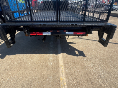 Isuzu NPR-HD flatbed truck rear view showing platform bumper and taillight assembly with hitch and safety bars.
