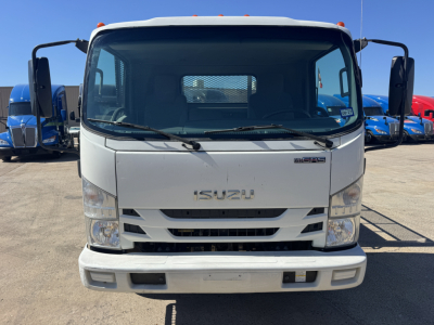 Isuzu NPR-HD truck front view showing Isuzu emblem, grille, and bumper in a flatbed truck lot.
